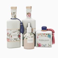 three bottles with flowers on them are next to each other and one has a blue ribbon