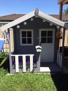 a small gray shed sitting on top of a lush green field next to a blue chair