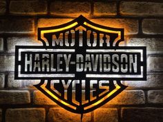 the harley davidson logo is lit up on a brick wall