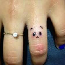 a person's hand with a ring on it and a panda face drawn on the middle finger