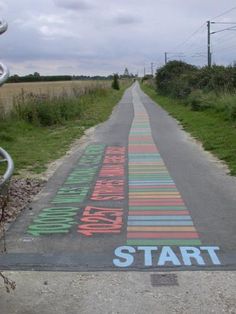 a painted street with the words start written on it in different colors and letters, along side a bike rack