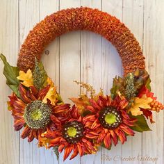 a knit wreath with sunflowers and autumn leaves on a white wooden background,