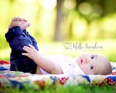 a baby laying on top of a blanket in the grass