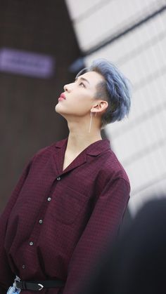 a woman with blue hair and piercings on her ears looking up to the sky