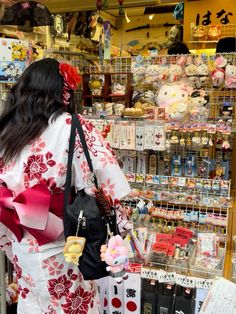 a woman in a kimono is looking at items on the shelves inside a store