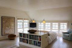 a bed room with a neatly made bed next to a book shelf filled with books