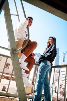 a man standing next to a woman on top of a metal ladder