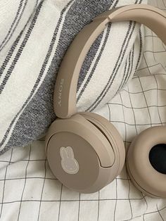 two headphones sitting on top of a bed next to a pillow