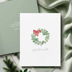 a card with the words joy to the world on it next to some greenery