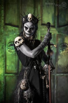 a woman dressed up as a skeleton holding a sculler and two skulls on her arm