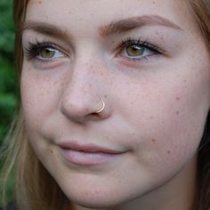 a woman with freckles on her nose looking at the camera while wearing a ring