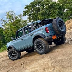 a blue pick up truck parked on top of a dirt road