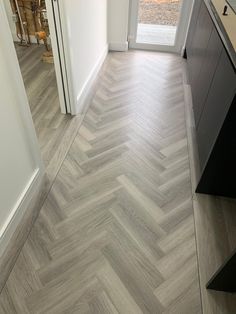 an empty hallway with wood flooring and white walls, leading to a patio door