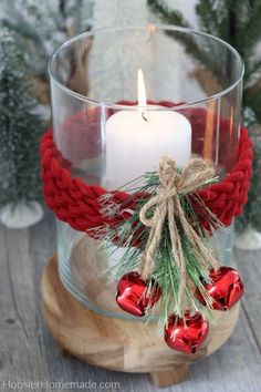 a candle is sitting in a glass bowl with red ornaments on it and a rope wrapped around the edge