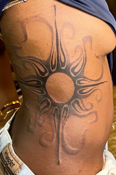 the back of a woman's stomach with an intricate tattoo design on her belly