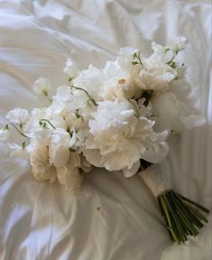 a bouquet of white flowers laying on top of a bed