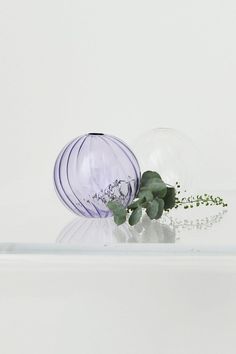 a glass vase with flowers in it sitting on a shelf next to another vase that is half empty