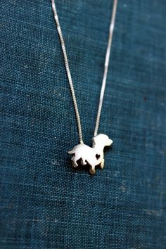 a silver dog necklace on a blue cloth