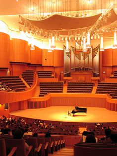 an auditorium filled with lots of seats and a piano on top of the stage in front of it