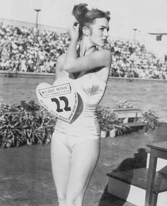 an old photo of a woman holding a frisbee in front of a crowd