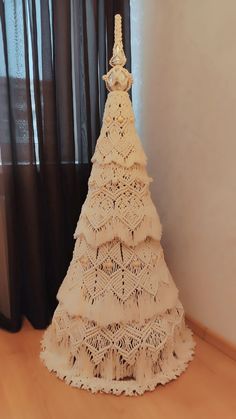 a white crocheted christmas tree sitting on top of a wooden floor next to a window