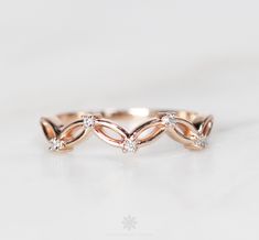 a rose gold wedding band with three diamonds on the top, and two leaves in the middle