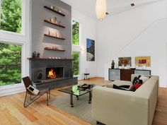 a modern living room with wood floors and white walls, along with an open fireplace