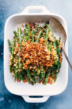 a white dish filled with green beans covered in crumbs