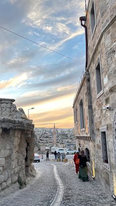 two people walking down a cobblestone street in an old city at sunset or dawn