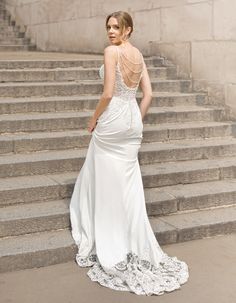 a woman in a wedding dress standing on some steps with her back to the camera