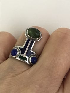 "There is a hint of arts and crafts, as well as, modernist in this unusual ring which you can wear with the Peridot facing up or down! The beautiful green stone, as well as the smaller vibrant blue Lapis are all cabochon and bezel set. The enamel is in wonderful condition. Aside from some slight wear, the ring is in overall fabulous shape. The band is almost 1/4\" wide, it is marked Sterling and has the initials CHM scratched on the silver behind the Peridot. Please see all photos for details, a Lapis And Peridot, Unusual Rings, Geometric Ring, Peridot Ring, Blue Lapis, Gold Snake, Charm Rings, Vibrant Blue, Silver Enamel