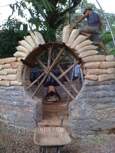 a man standing on top of a wooden wheel