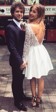 a man and woman standing next to each other in front of a double decker bus