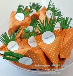 orange and white paper flowers in a bowl with name tags on the top for each flower