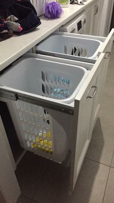 a kitchen with white cabinets and drawers filled with plastic bins