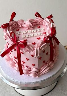 a heart shaped cake with red ribbon and bow around it's edges that says twenty five