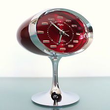 a red clock sitting on top of a metal stand