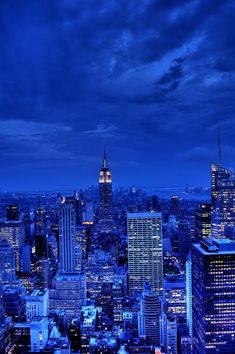 the city skyline is lit up at night, with skyscrapers in the foreground