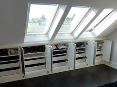 an attic bedroom with white storage cabinets and skylights on the windows sill above