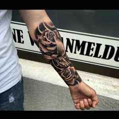 a man with a black rose tattoo on his arm and hand is holding the wrist