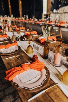 a table set up with orange napkins and place settings