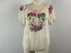 "Vintage 1940s embroidered bohemian blouse. Made of sheer white Rayon/Nylon. Ethnic shirt with embroidered purple pink and green flowers. Has drawstring neckline and drawstring at cuffs. About a size large, but would work one size fits all. Actual measurements are:  41\" at the bust  43\" at the waist  18\" shoulder to shoulder  22\" overall length In very good condition with a couple of faint spots, see picture." Fitted Bohemian Embroidered Blouse, Fitted Bohemian Peasant Top With Floral Embroidery, Pink Folk Blouse For Spring, Bohemian Fitted Short Sleeve Blouse, Fitted Short Sleeve Bohemian Blouse, Fitted Bohemian Short Sleeve Blouse, Bohemian Fitted Embroidered Top For Spring, Folk Style Fitted Blouse For Spring, Vintage Blouse For Spring Festival