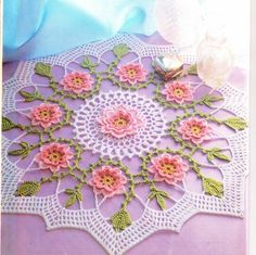 a crocheted doily with pink flowers on it