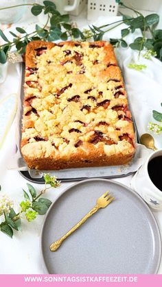 there is a cake with berries on it next to a plate and cup of coffee