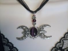 "This beautiful necklace has a sterling silver plated filigree pendant with a triple moon design, purple catseye setting and a beautiful black organza ribbon. 18\" long. Lobster clasp." Gothic Festival Jewelry With Moon Charm, Mystical Handmade Necklace For Wedding, Gothic Pendant Jewelry For Larp, Handmade Gothic Necklaces For Larp, Handmade Mystical Necklace For Wedding, Nickel-free Silver Witchy Jewelry, Silver Nickel-free Witchy Jewelry, Adjustable Silver Witchy Jewelry, Handmade Gothic Crescent Jewelry