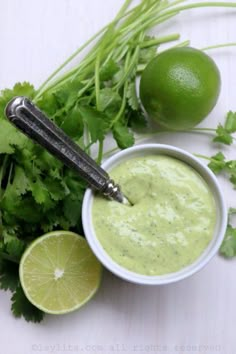 limes and cilantro are on the table next to a bowl of dip