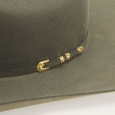 Stand out from the crowd in the Stetson Sage Munford hat. The classic and refined style is a textured staple, made of genuine 6x fur felt material. The matching hatband is accented by the focal point of this hat, the gold and silver buckle set dotted by green stones that set the entire look apart. Add this unparalleled and timeless beauty to your collection for a true western look. Elegant Adjustable Gold Felt Hat, Elegant Gold Adjustable Felt Hat, Western Style Formal Top Hat With Flat Crown, Classic Gold Fedora With Curved Brim, Classic Gold Hat Band For Fedora, Classic Gold Flat Brim Hat Band, Classic Gold Fedora With Short Brim, Classic Gold Brimmed Fedora, Classic Gold Flat Brim Fedora