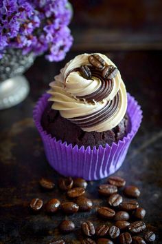 there is a cupcake with frosting and coffee beans on the table