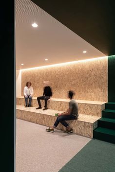 three people sitting on some steps in front of a wall with green and white stripes