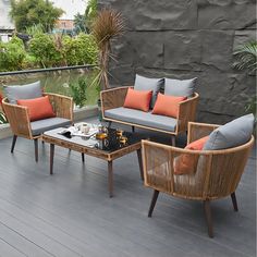 an outdoor living area with furniture and plants on the deck, along with a stone wall